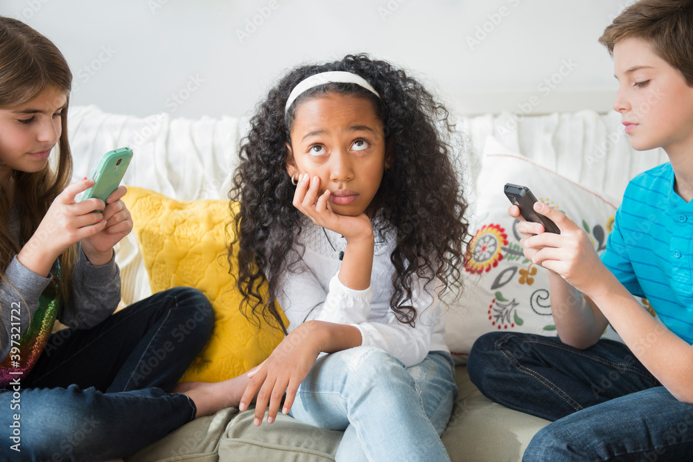 © JGI/Jamie Grill/Blend Images - Annoyed girl ignoring friends using cell phones on sofa © JGI/Jamie Grill/Blend Images - Annoyed girl ignoring friends using cell phones on sofa