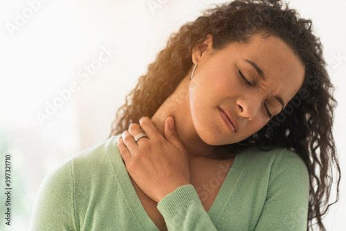 Close up of mixed race woman rubbing sore neck photo
