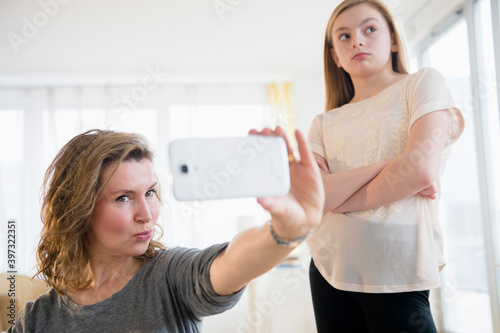 Caucasian girl embarrassed of mother taking selfies with cell phone