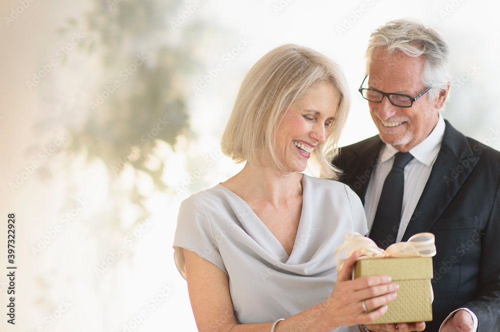 Smiling older Caucasian man giving wife a gift Smiling older Caucasian man giving wife a gift