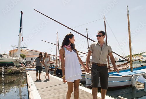 Couple walking on wooden dock in urban harbor