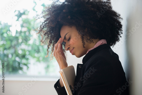 Stressed mixed race businesswoman rubbing her forehead photo