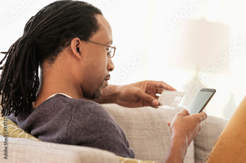 Black man shopping with cell phone on sofa photo