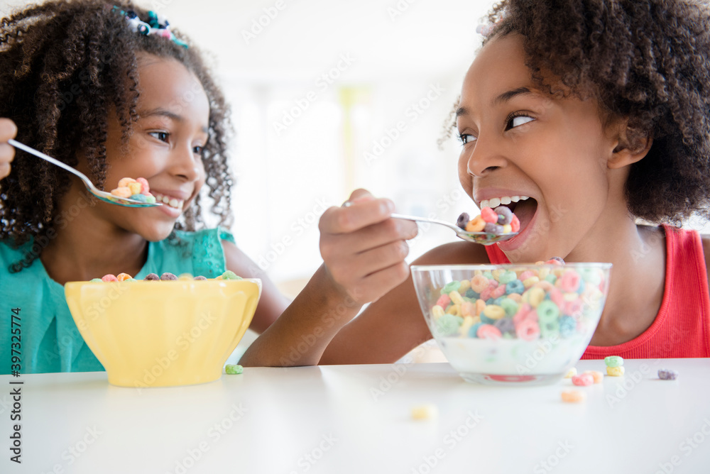 Mixed race sisters eating cereal Mixed race sisters eating cereal