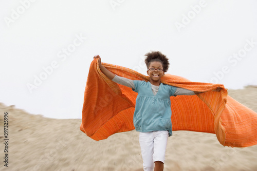 Mixed race girl playing with blanket at beach