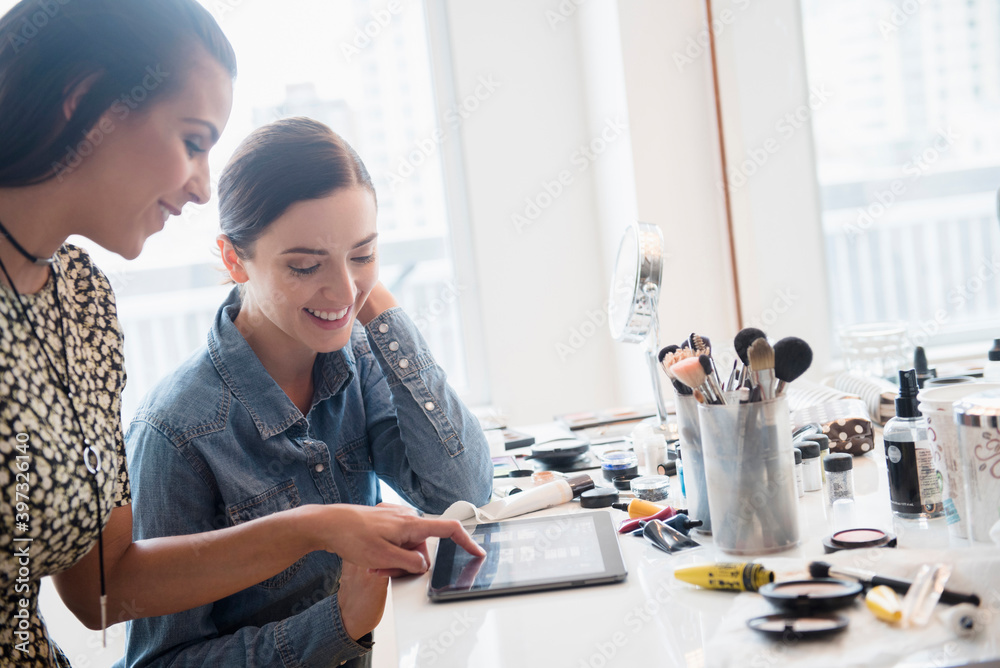 Makeup artist using digital tablet with client Makeup artist using digital tablet with client