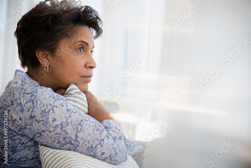 Pensive older Black woman clutching pillow