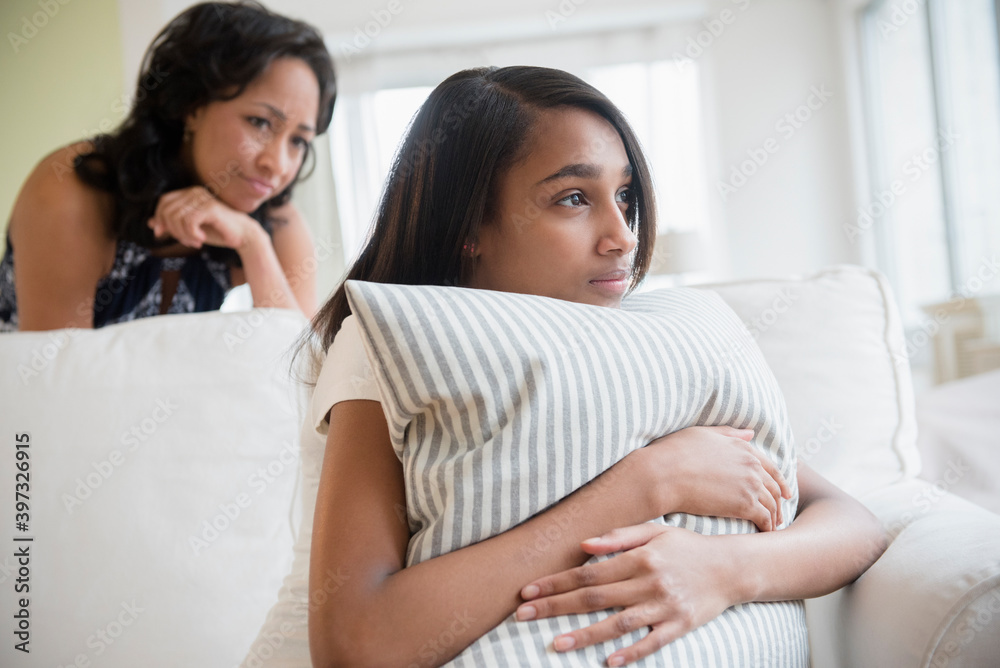 Mother watching pensive daughter clutching pillow Mother watching pensive daughter clutching pillow