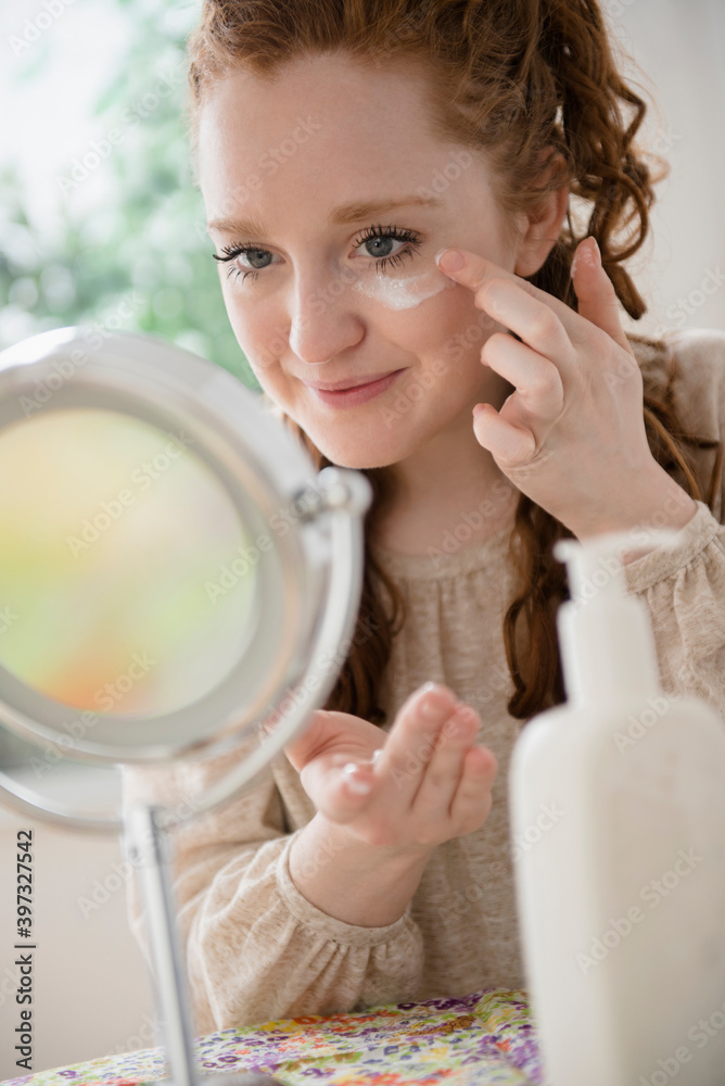 Caucasian woman applying moisturizer to face Caucasian woman applying moisturizer to face