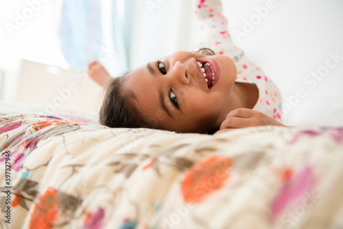 Smiling Mixed Race girl rolling on bed photo