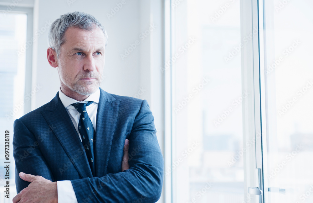Pensive older Caucasian businessman looking out window Pensive older Caucasian businessman looking out window