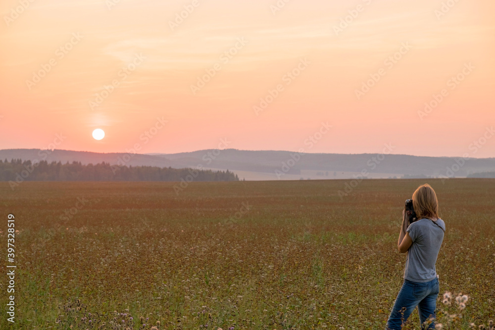 Caucasian woman photographing sunset in field Caucasian woman photographing sunset in field