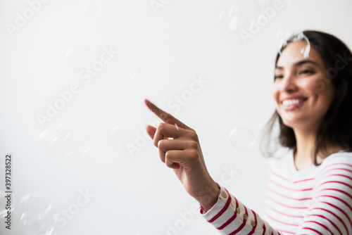 Hispanic woman popping floating bubbles photo