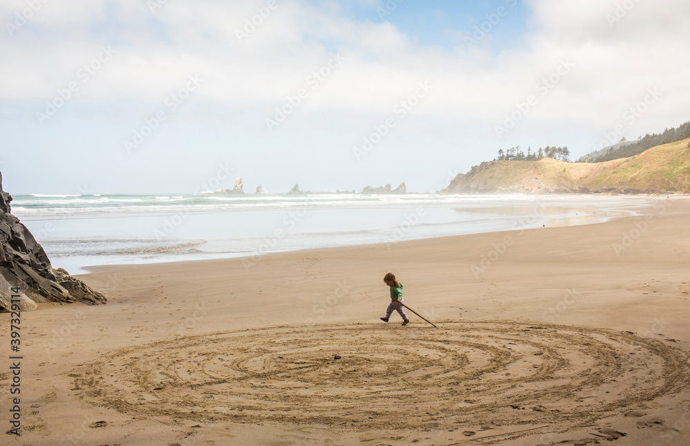 Caucasian girl drawing circles on beach with stick Caucasian girl drawing circles on beach with stick
