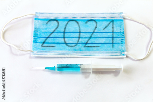 Maseczka chirurgiczna z napisem 2021 i strzykawka. Temat masowych szczepień przeciwko koronawirusowi w 2021 roku photo