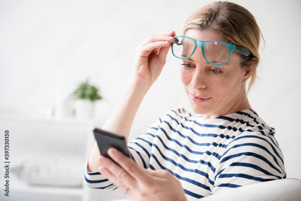 Caucasian woman lifting eyeglasses reading cell phone Caucasian woman lifting eyeglasses reading cell phone