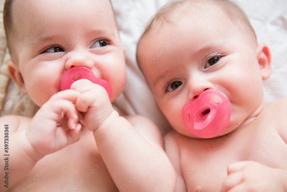 Caucasian twin baby girls sucking pacifiers Caucasian twin baby girls sucking pacifiers