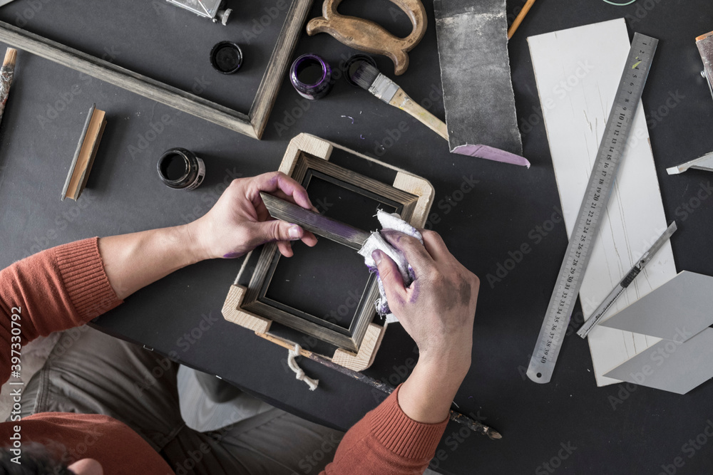 Hands of Caucasian artist staining picture frame