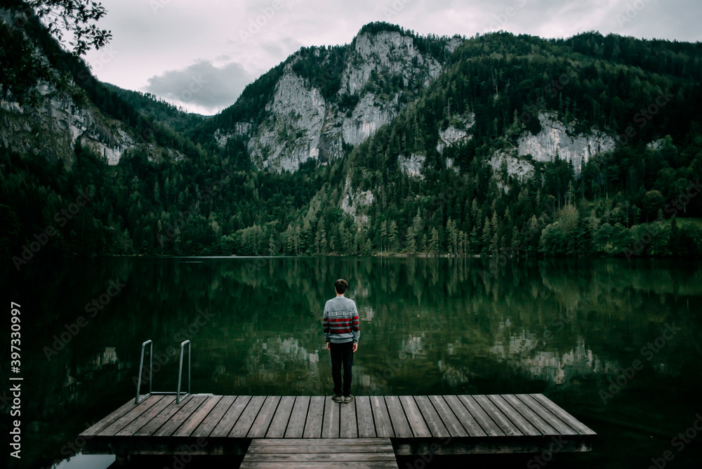 Caucasian man standing on dock admiring scenic view of mountain Caucasian man standing on dock admiring scenic view of mountain