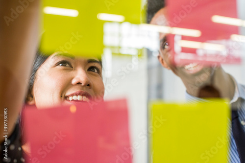 Woman and man reading adhesive notes in office photo