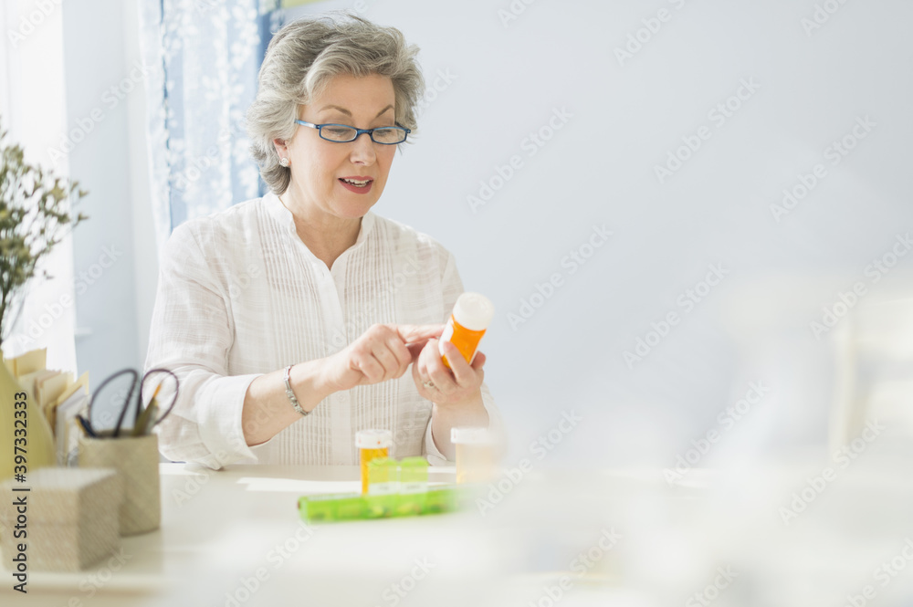 Mature woman reading labels on medicine bottle Mature woman reading labels on medicine bottle