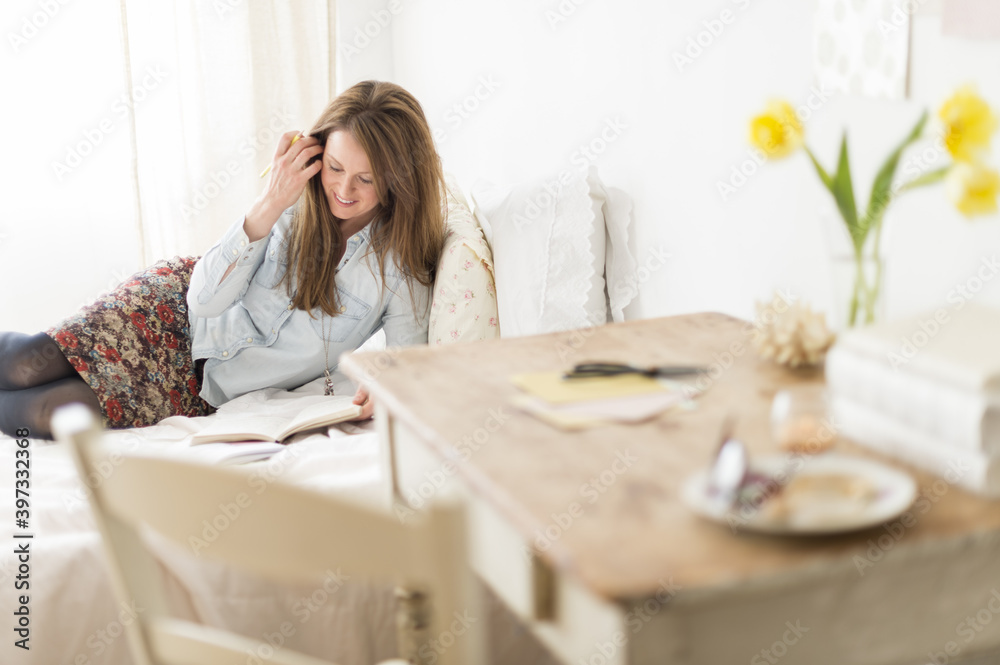 Woman lying on bed and writing diary Woman lying on bed and writing diary