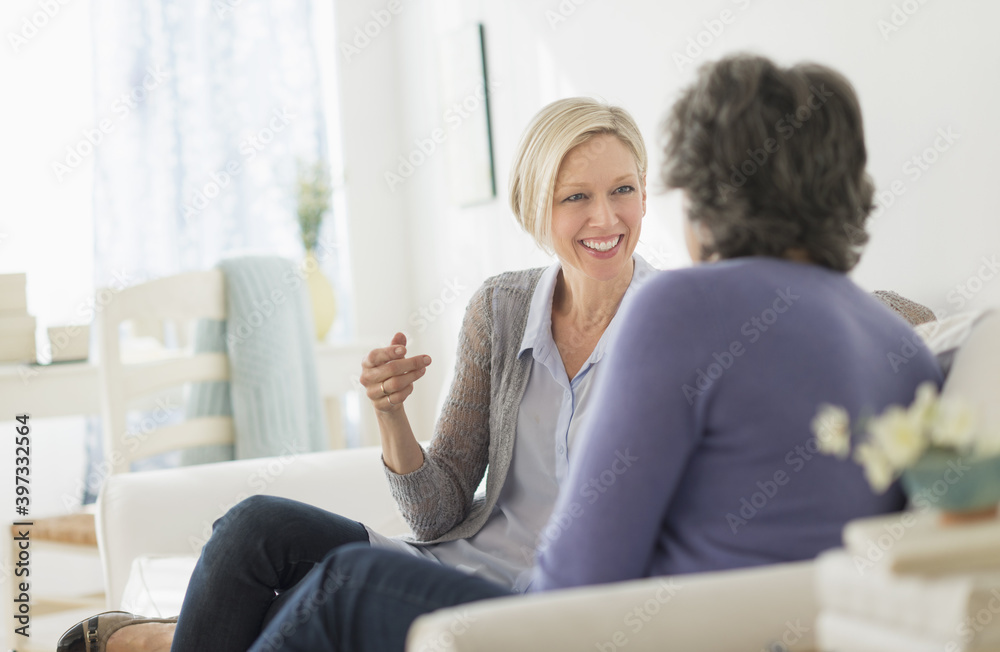 Two women sitting on coach talking Two women sitting on coach talking