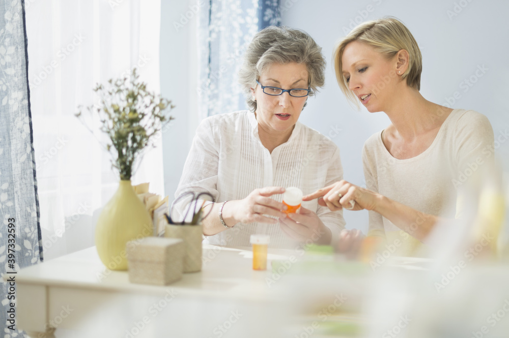 Nurse and mature woman reading labels on medicine bottle Nurse and mature woman reading labels on medicine bottle