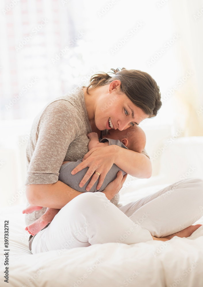 Mother embracing baby boy (2-5 months) in bed Mother embracing baby boy (2-5 months) in bed