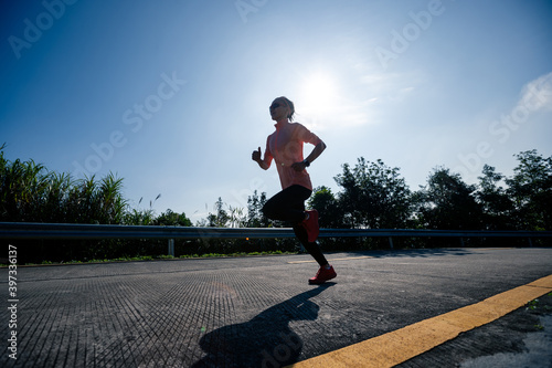 Woman runner running on sunrise mountain top on winter day