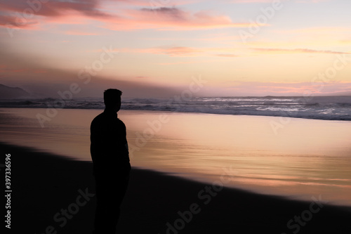 silueta de hombre en un atardecer en la playa con tonos narajas