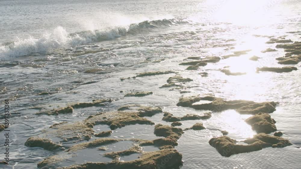 Slow motion picturesque waterscape with ocean waves washing the coast with rocks in bright sunlight. Water glistening in the sun. Lanzarote scene, Canary Islands Slow motion picturesque waterscape with ocean waves washing the coast with rocks in bright sunlight. Water glistening in the sun. Lanzarote scene, Canary Islands