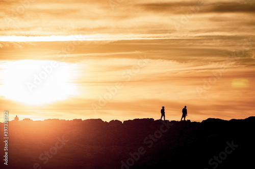 Silhouette of two men at beautiful sunset on the coast