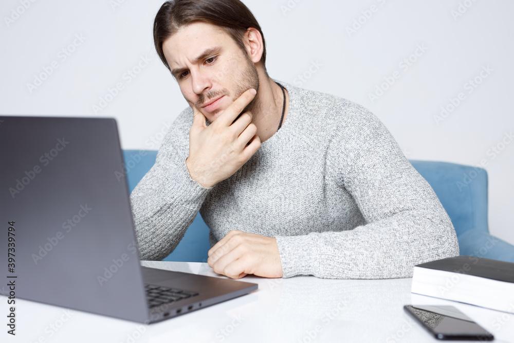 Guy browsing internet on computer and expresses emotions.  Young man working on laptop.