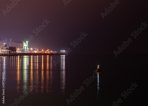 buoy in the sea with illuminated city in the background