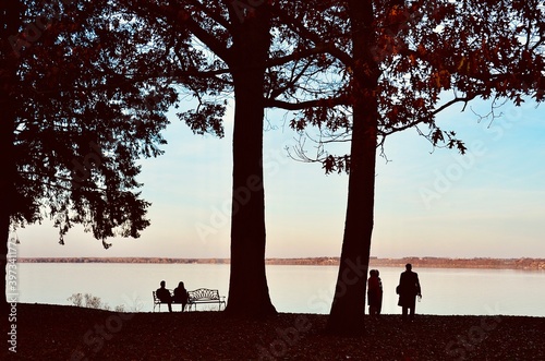 View of Seneca Lake (one of Finger Lakes) at sunset. Group of people enjoying the natural scene, while chatting and drinking (alcohol beverage from the onsite winery). 
