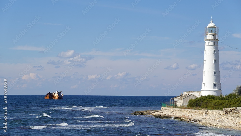 White lighthouse and a sunken ship in the Black Sea, landscape of the Tarkhankut coast, Crimean Peninsula in Russia.