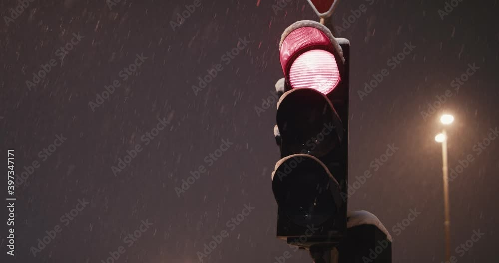 Traffic light turn red yellow green on a cold winter night snowfall