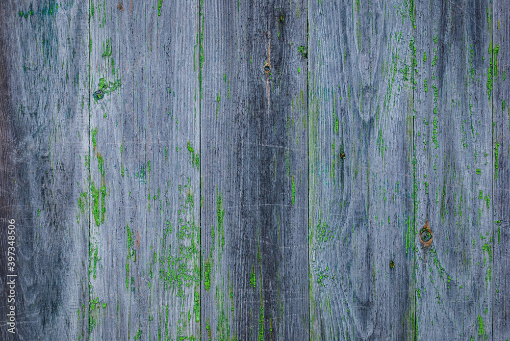 gray faded wooden wall with remnants of peeling green paint and spots of rot