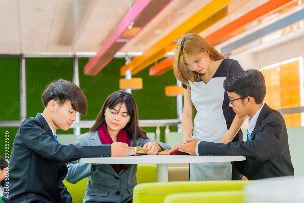 © shine - Group of Young asian lawyer reading legal book together in the law library at the university.
