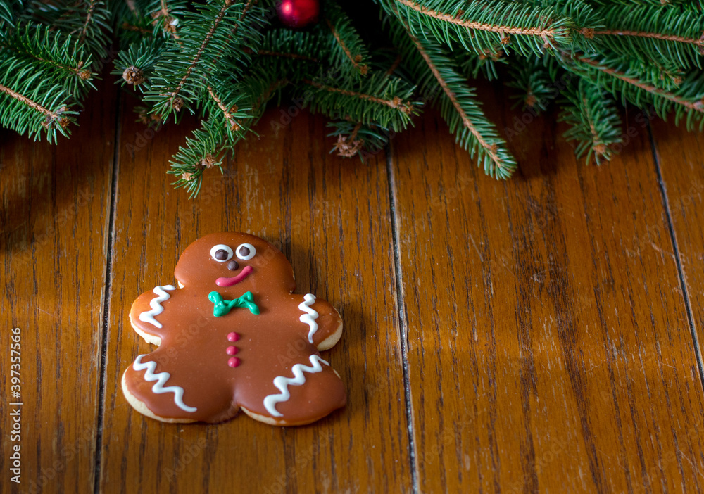 gingerbread cookie with room for text, against a wood table backdrop with evergreen branches gingerbread cookie with room for text, against a wood table backdrop with evergreen branches