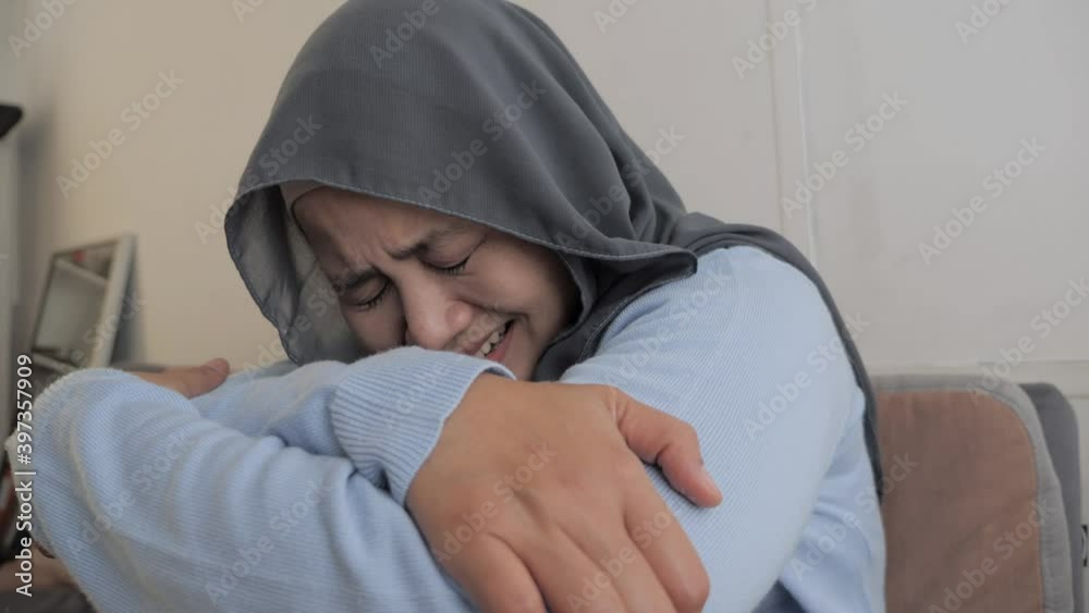 Sad Asian muslim woman wearing hijab crying, suffering from headache pain or having stress depression