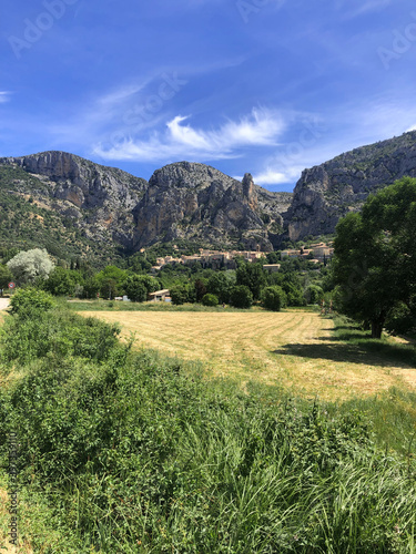 Beautiful outside view of Moustiers Sainte Marie with rocks mountain and green grass field, one of beautiful tourist village in Provence, Southern France.