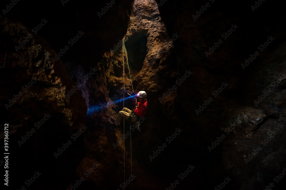 Rescuers or climber descends in a cave fast rope in the dark caves