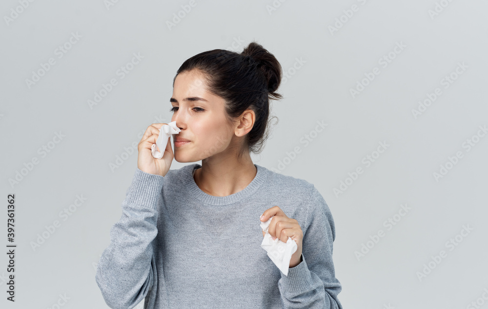 Woman in sweater holding napkin near face with runny nose health problems cropped view
