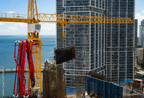 Crane lowering metal mold for formwork in preparation of pouring concrete at downtown Miami high rise skyscraper construction project 