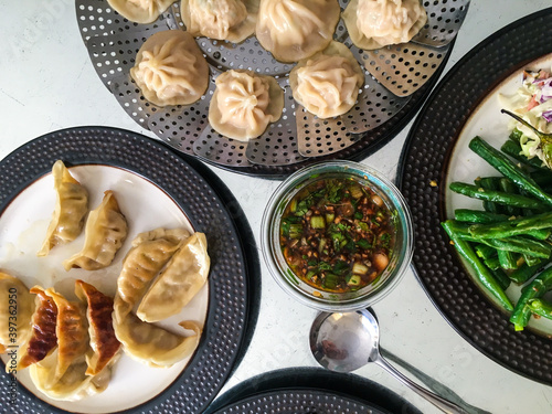 Traditional soup dumplings and other Taiwanese food on plates filling a table from an overhead view