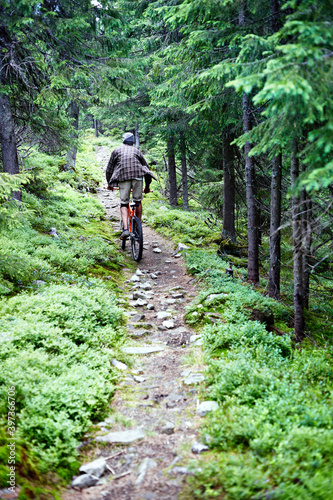 Young caucasian cyclist on a mountain bike rides along mountain trails in a mountain forest.