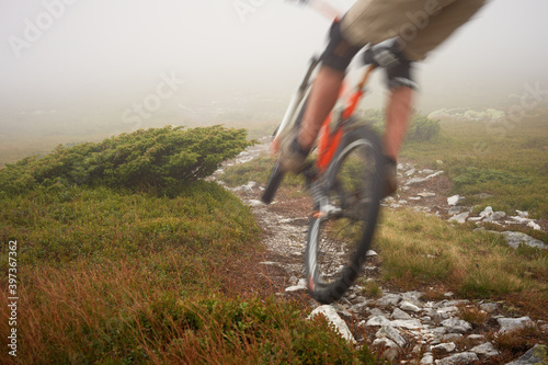 Blurred in motion mountain biker drives down from the mountain peaks