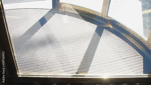 Sunlight reflects in mechanical revolving door with golden framing and carpet operating in hotel close view slow motion. Concept hotel interior